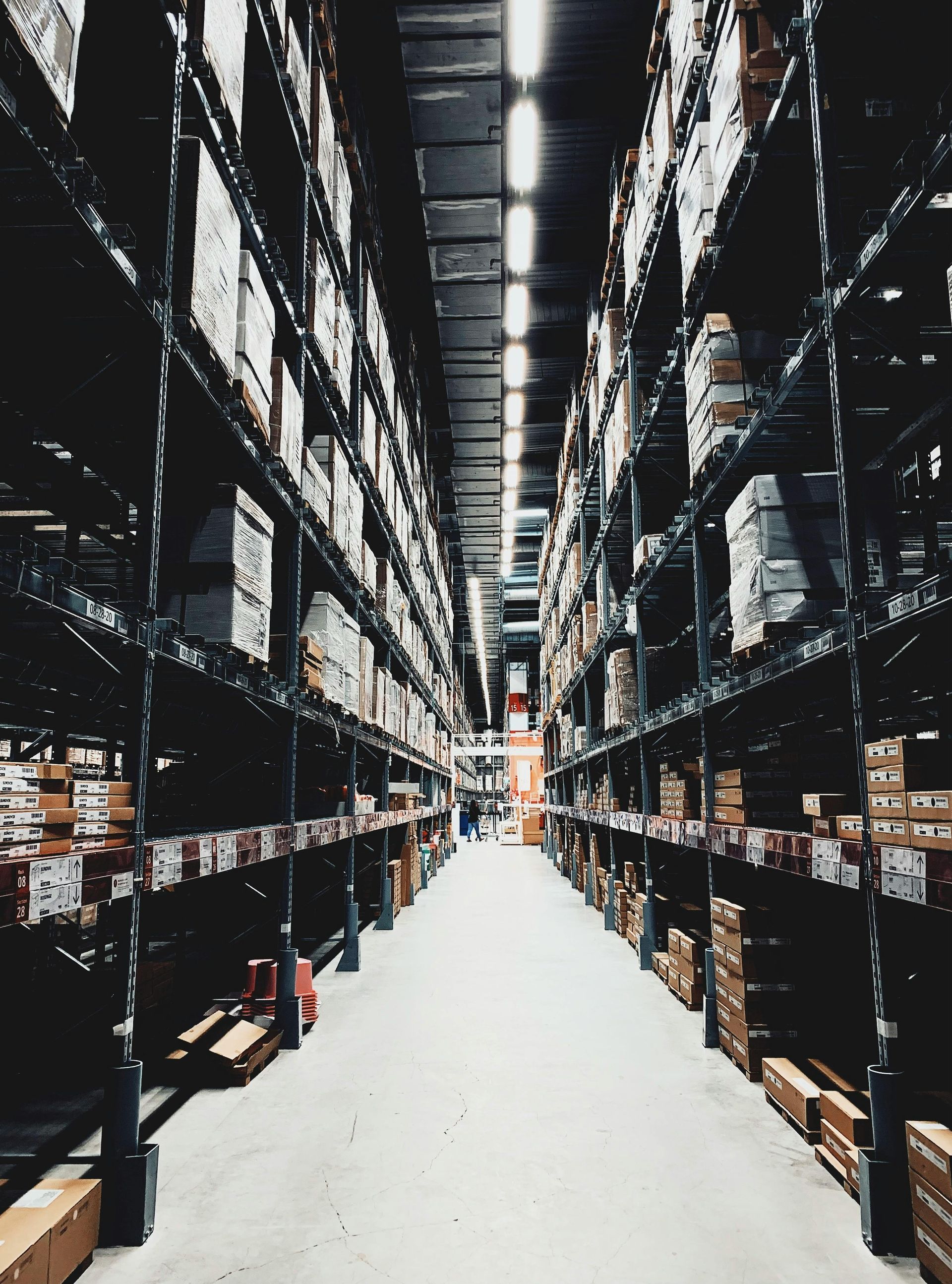 Warehouse aisle with rows of shelves filled with boxes and products.