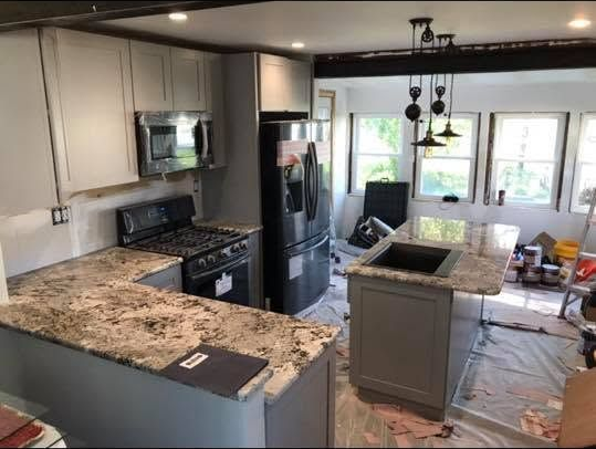 Modern kitchen with granite countertops, stainless steel appliances, and sunlight through windows