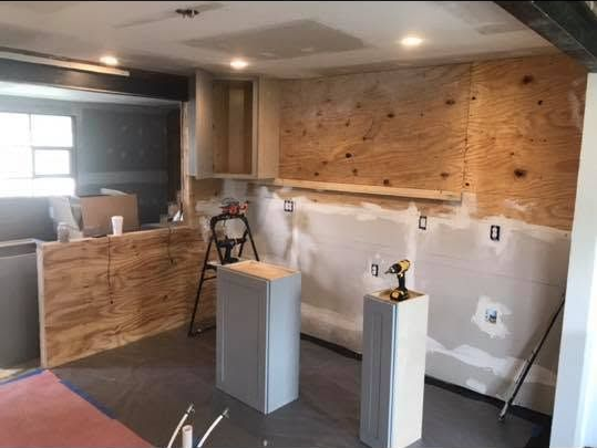 Partially renovated room with exposed wall studs, white drywall, and two pedestal stands with tools.