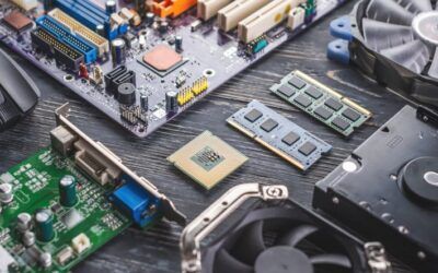 Primo piano di componenti di computer e circuiti stampati sparsi su una scrivania, tra cui moduli RAM e un chip CPU.