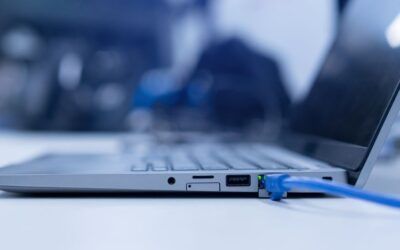Un laptop argentato con un cavo Ethernet blu collegato a una scrivania