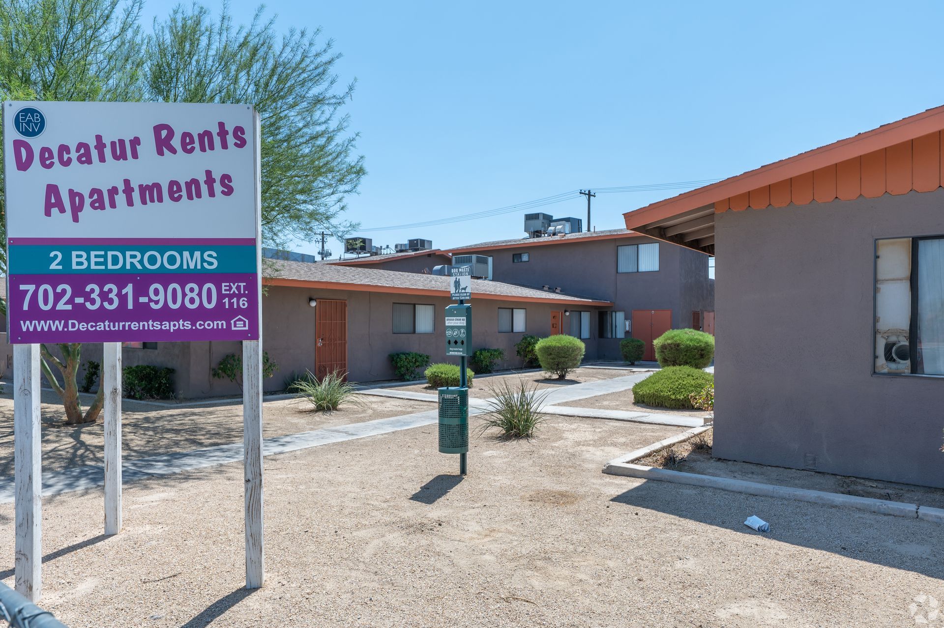 Decatur Rents Apartments sign in a desert-style apartment complex with tan buildings and gravel courtyard