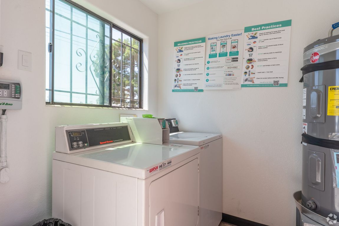 Laundry room with white washer and dryer, window, wall posters, and a water heater on the right.