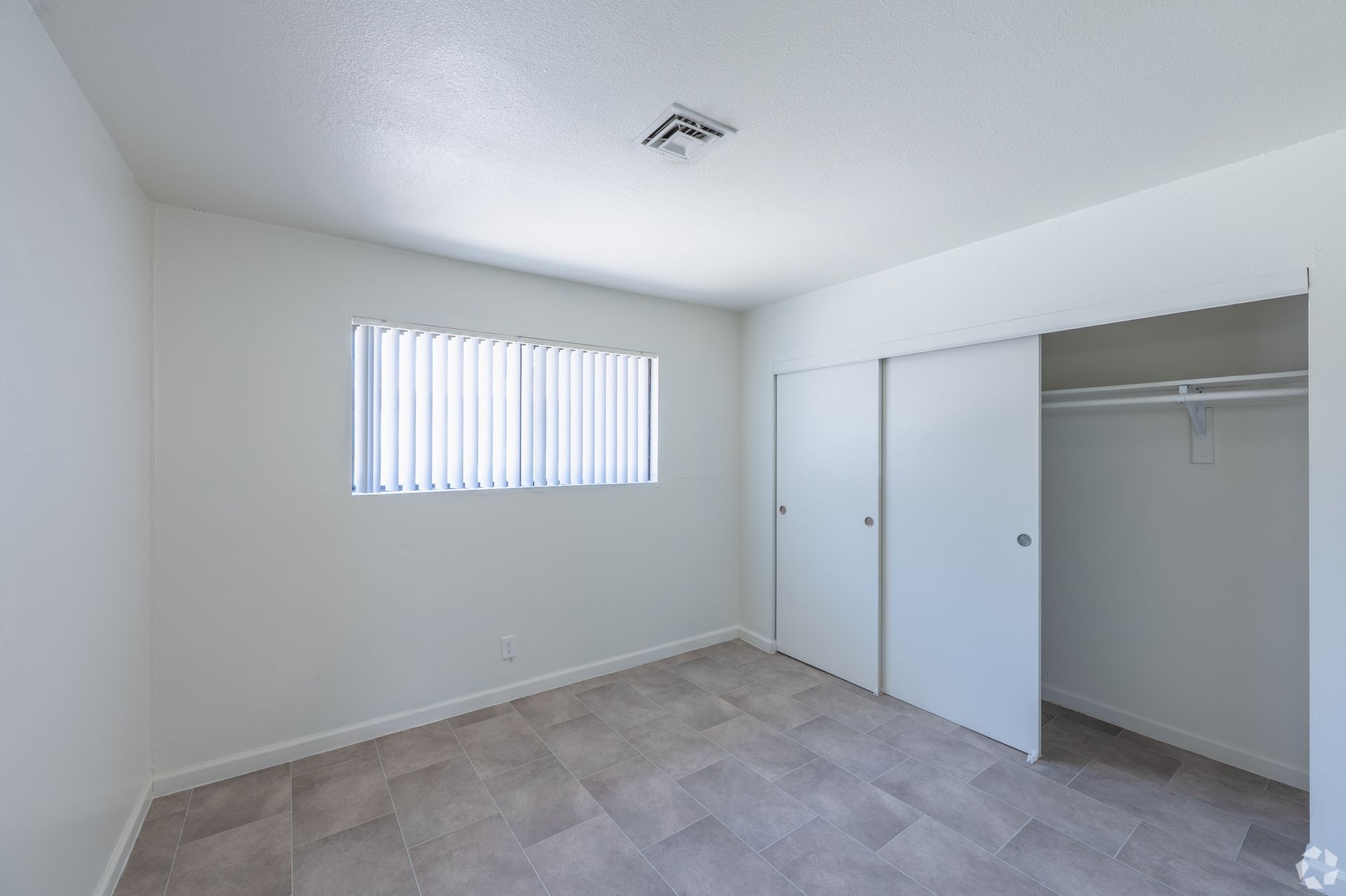 Empty white bedroom with closet, window blinds, and carpeted floor