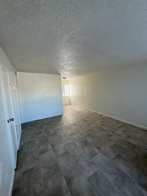 Empty white room with gray tile floor and a bright doorway at the far end