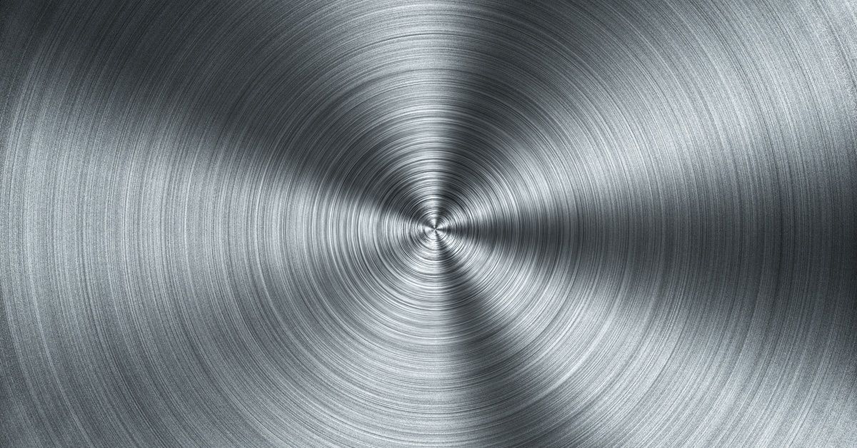 Close-up of a brushed metal surface with a circular grain pattern, creating textured radial lines in