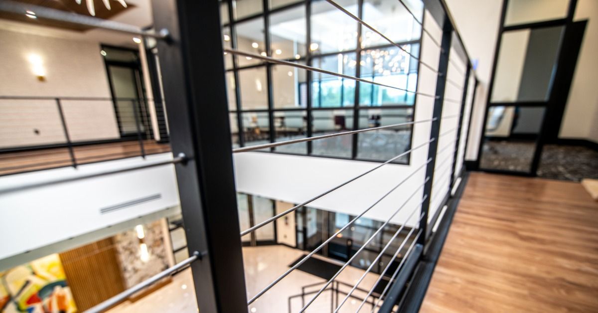 Modern interior with black cable railing along an upstairs walkway overlooking an open-concept space