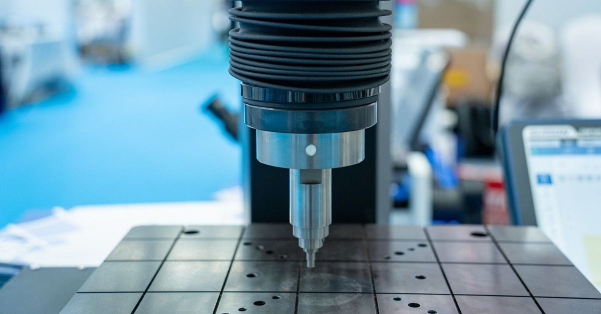 A hardness testing machine applies an indenter to a flat metal specimen during laboratory material testing.