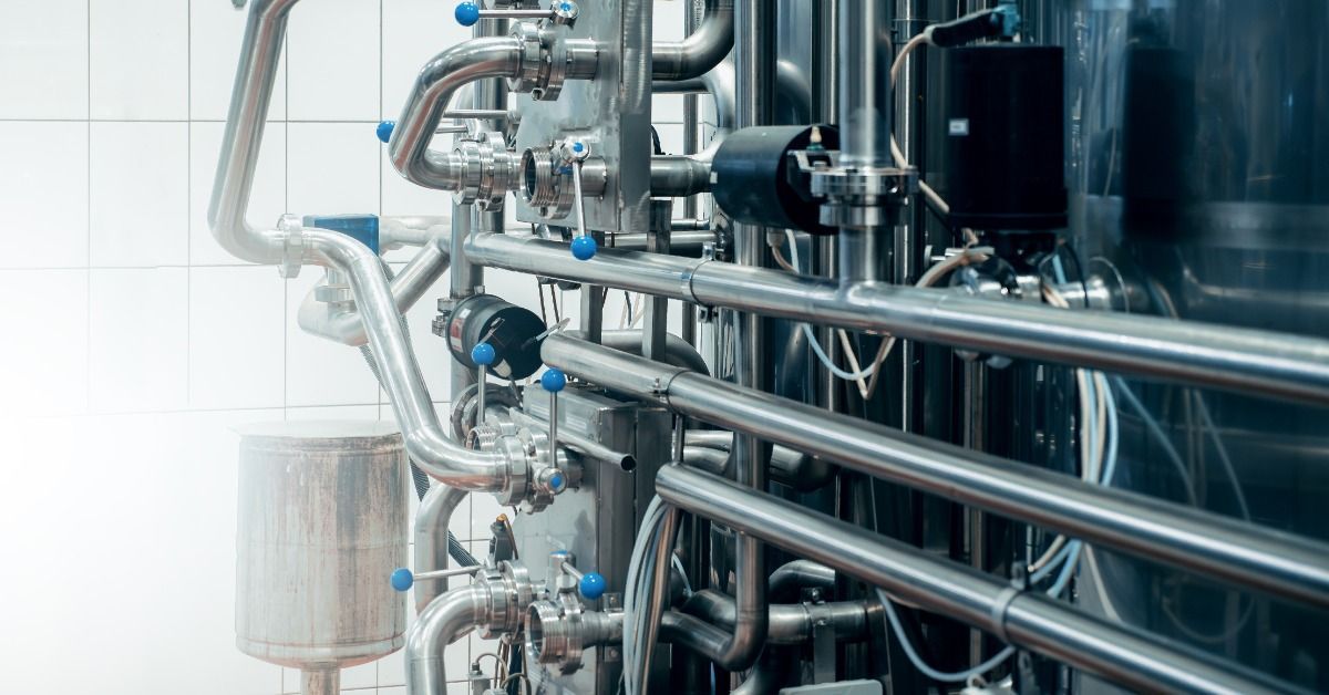 Polished stainless steel pipes with valves and bends form an interconnected flow system.