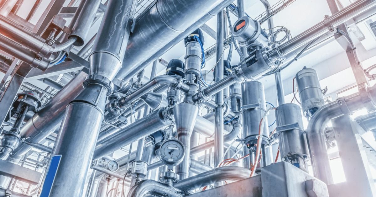 Industrial stainless steel piping and processing equipment run throughout a large manufacturing faci