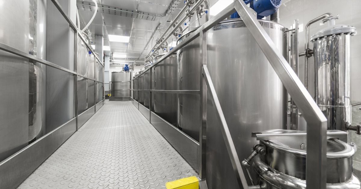 A raised metal walkway runs between stainless steel processing tanks and equipment.