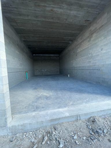 Empty concrete storage bay with unfinished walls and ceiling, viewed from the entrance.