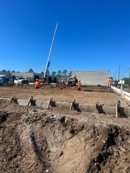 Construction site with excavator and workers near a trench under a clear blue sky