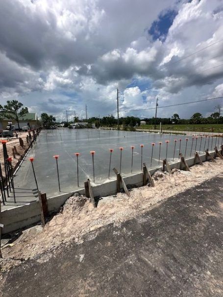 Concrete foundation site with rebar and wooden forms under a cloudy sky