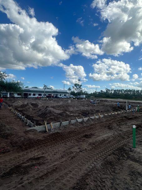 Construction site with dirt excavations under a bright blue sky with large white clouds