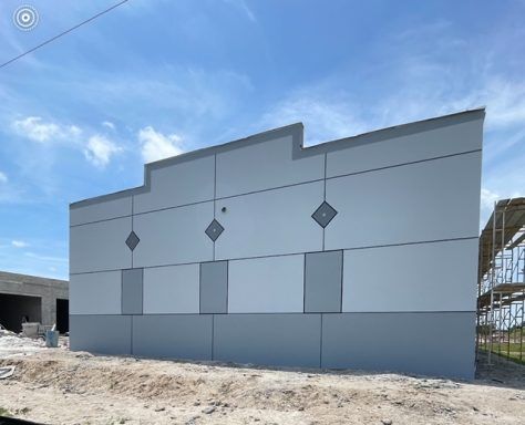 Gray industrial building wall with diamond accents under construction against a blue sky
