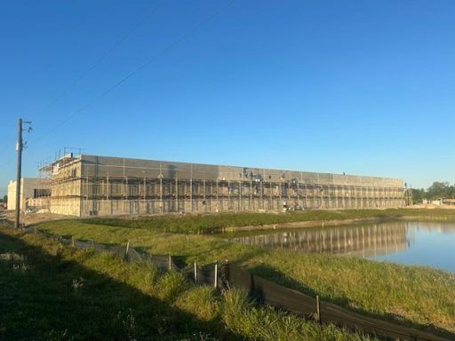 Long beige building beside a calm waterway under a clear blue sky