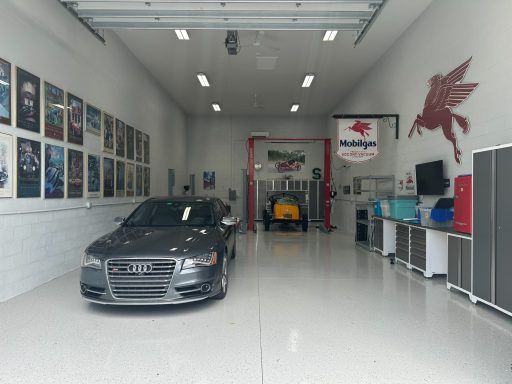 Car in a bright auto shop garage with tools, wall art, and workbenches along the sides