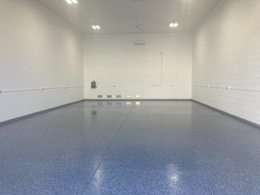 Empty white room with blue floor and wall outlets, viewed from the doorway
