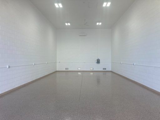 Empty white tiled room with polished floor and overhead lights