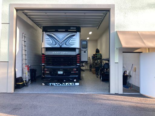 Truck parked inside an open garage with a large white and black cab facing out.