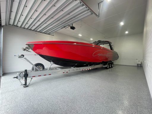 Red speedboat on a trailer inside a white garage with a gray floor.