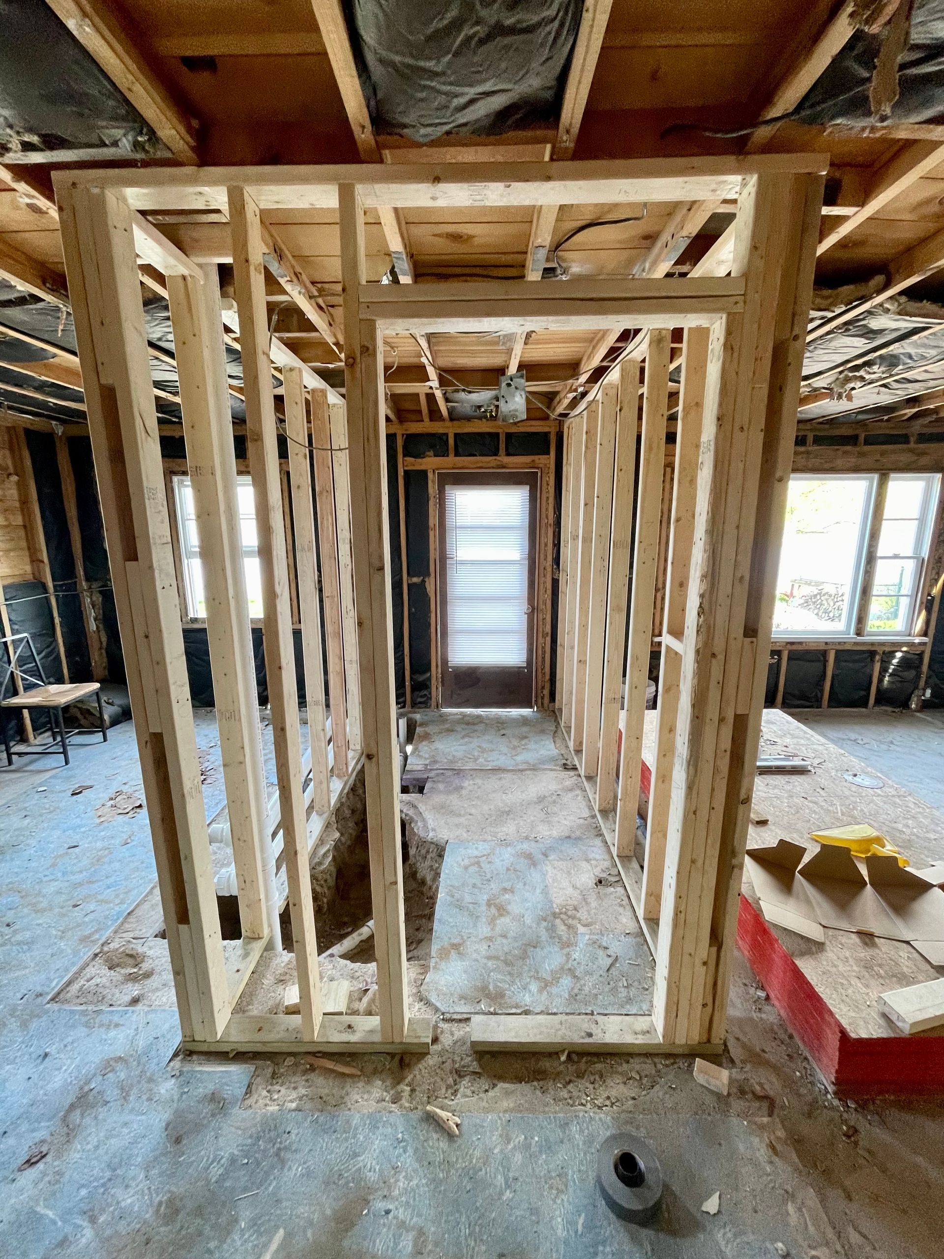Framed interior hallway under construction with exposed studs and a doorway at the end.