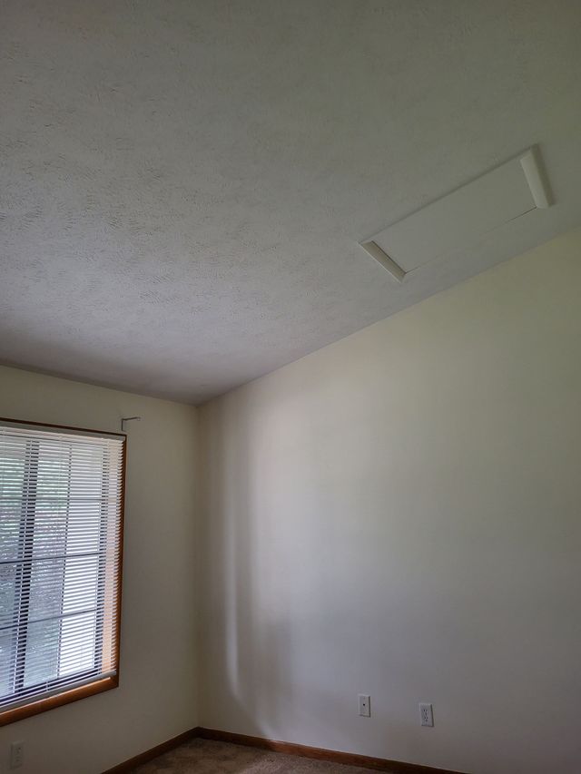 Person standing on a step ladder installing cabinet doors in a room under renovation.