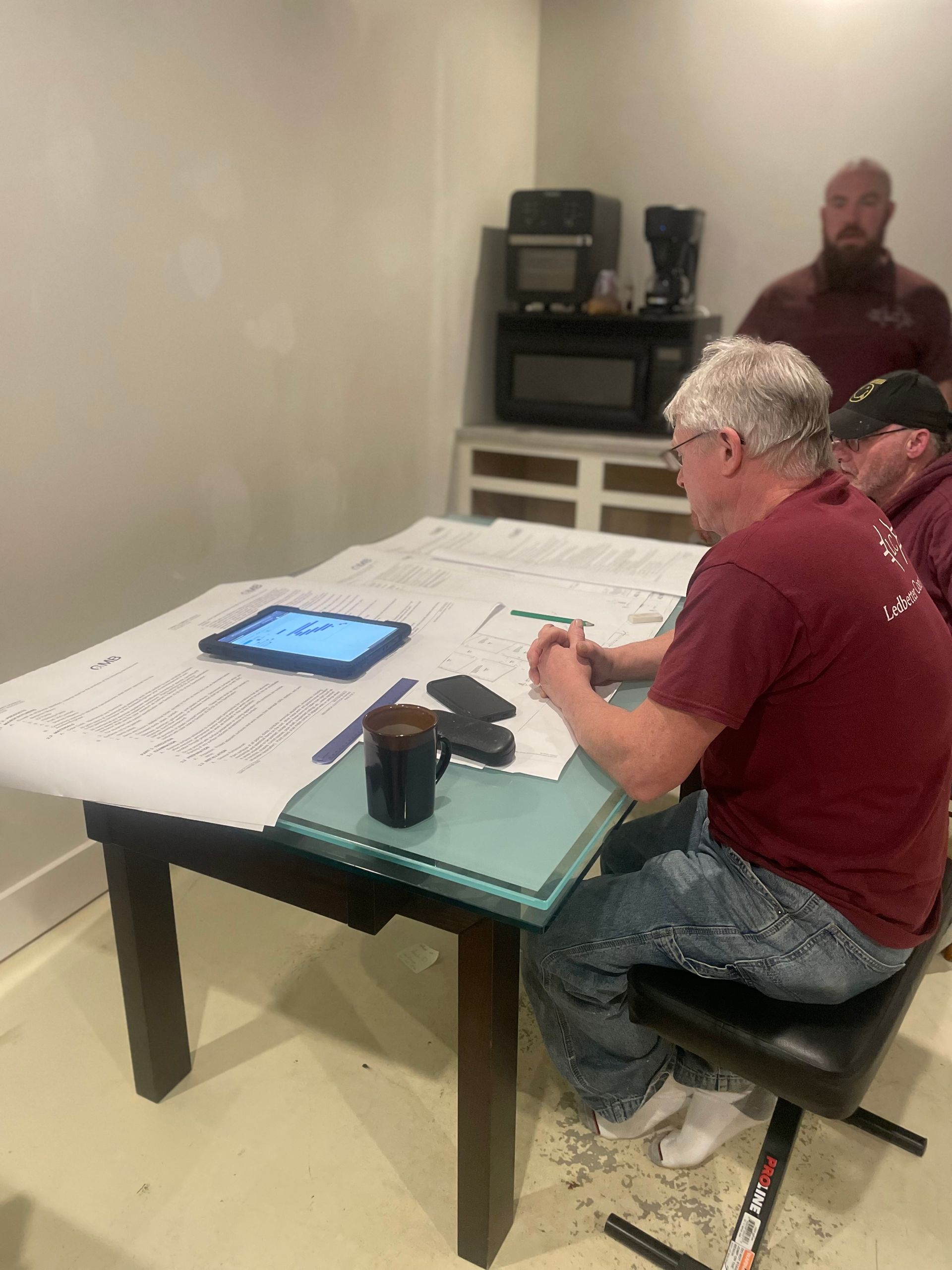 Two people seated at a table reviewing items on a tablet in a plain room.