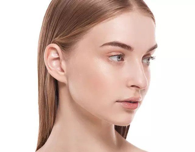 A woman is laying on a bed with a sheet mask on her face.