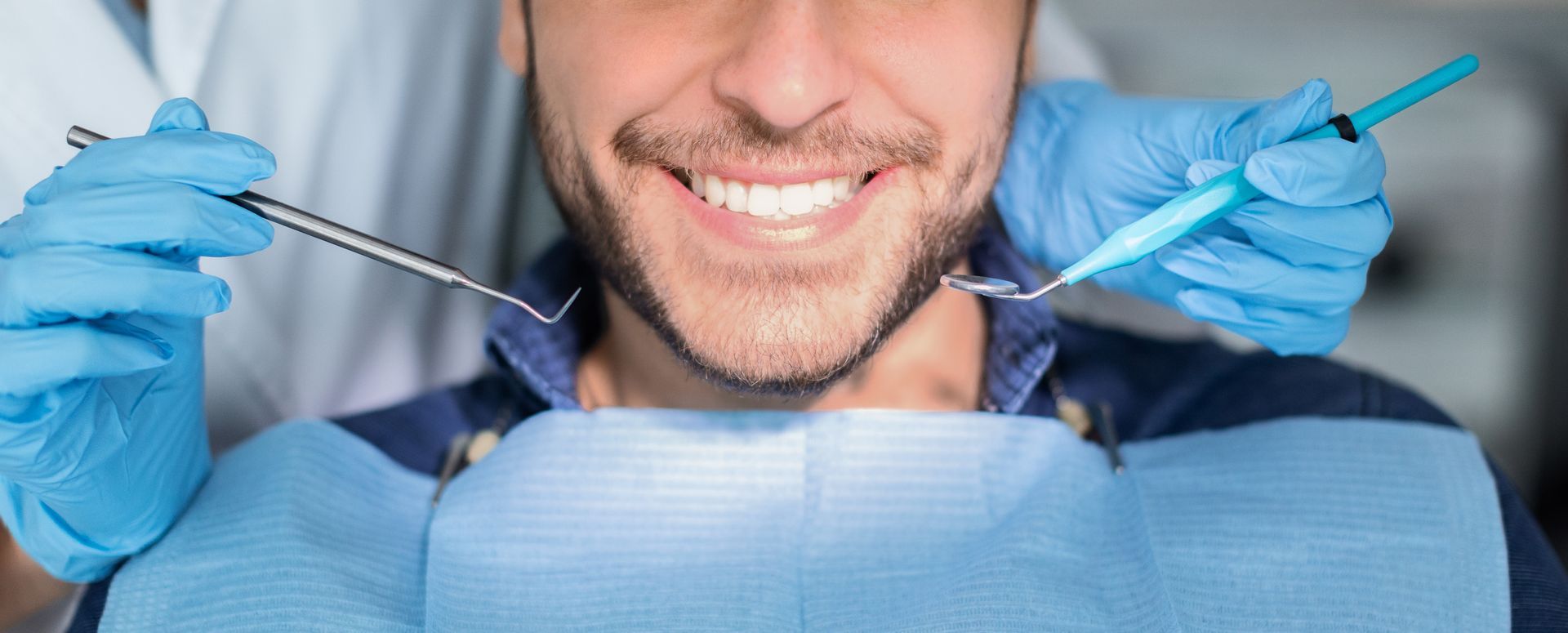 Male patient having teeth whitening procedure at modern dental clinic, smiling at camera.