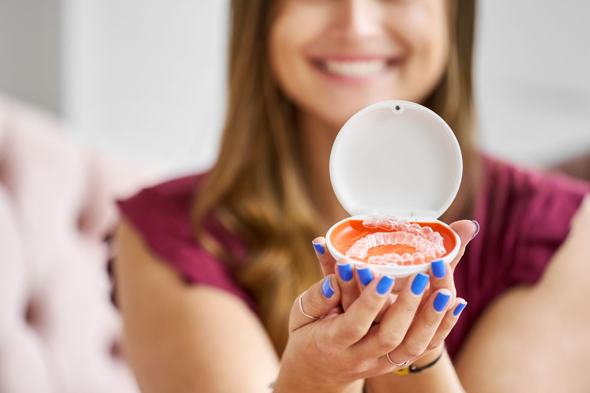 A woman with blue nails is holding a box of teeth.