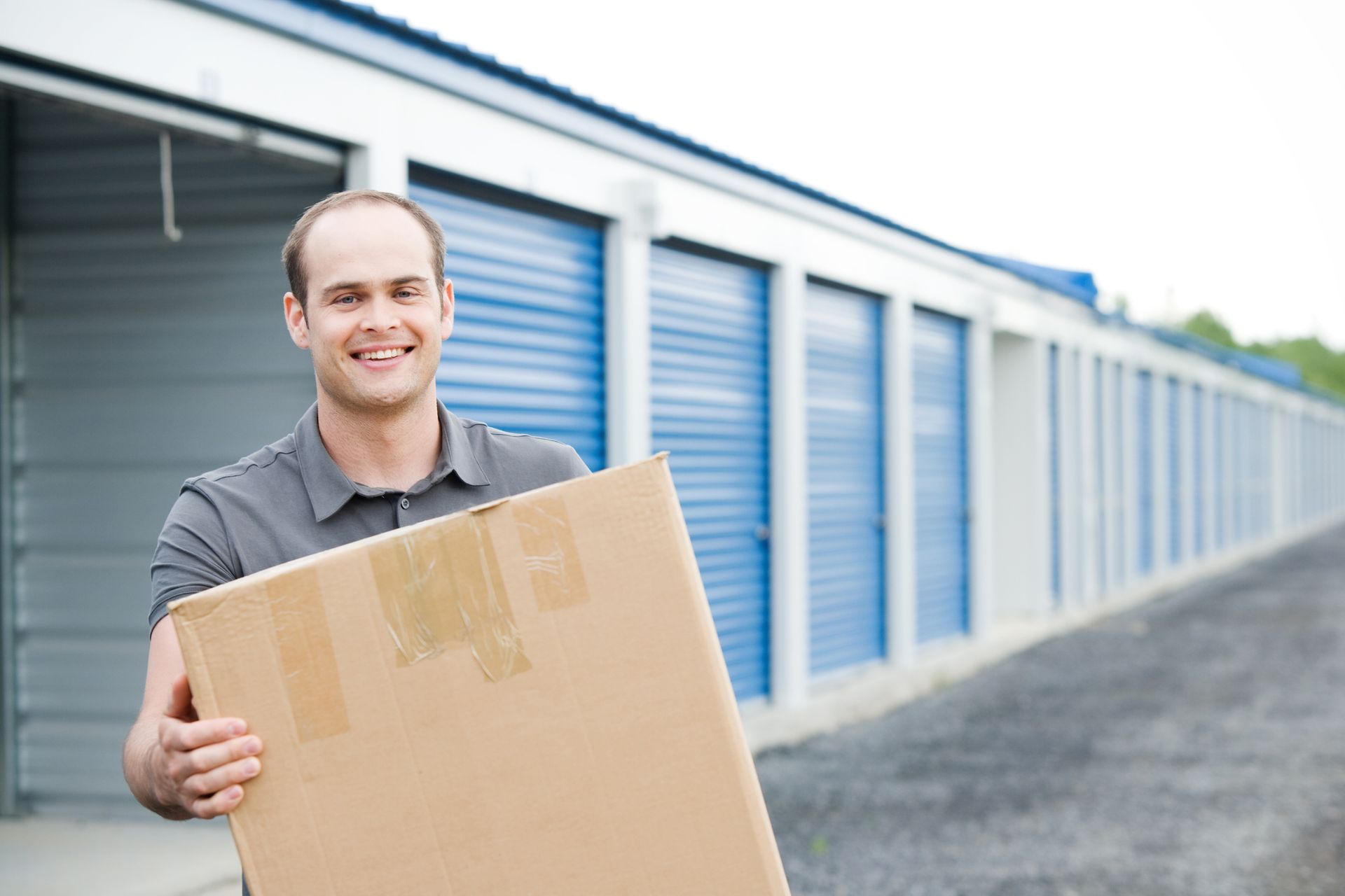 Green storage unit doors line a long, narrow hallway.