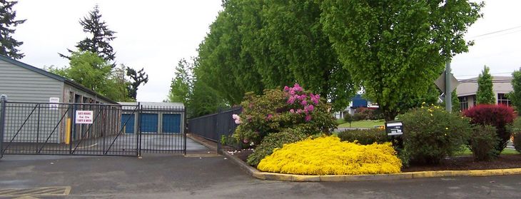 Orange storage unit doors with gray roofs against a backdrop of trees. Orange storage unit doors with gray roofs against a backdrop of trees.