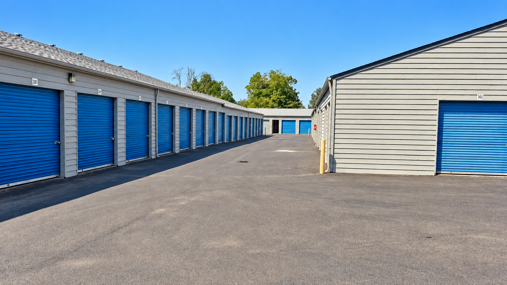 Green storage unit doors line a long, narrow hallway. Green storage unit doors line a long, narrow hallway.