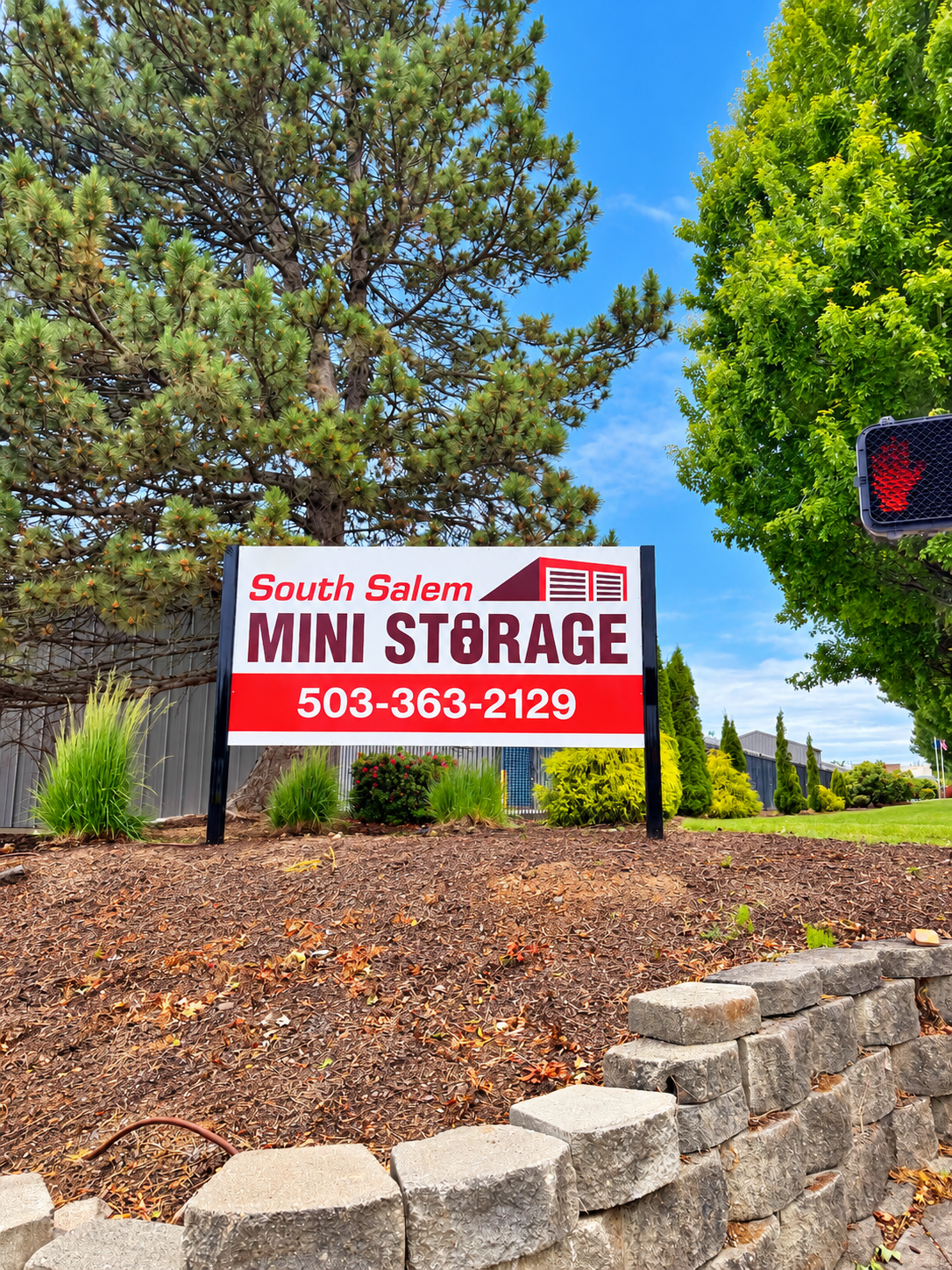 Man holding a large cardboard box smiles in front of blue storage units.