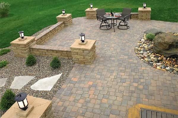 Brick patio with seating area, stone pillars with lights, landscaping.