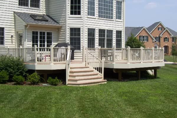 Back view of a multi-level wooden deck with steps leading to a green grassy yard.