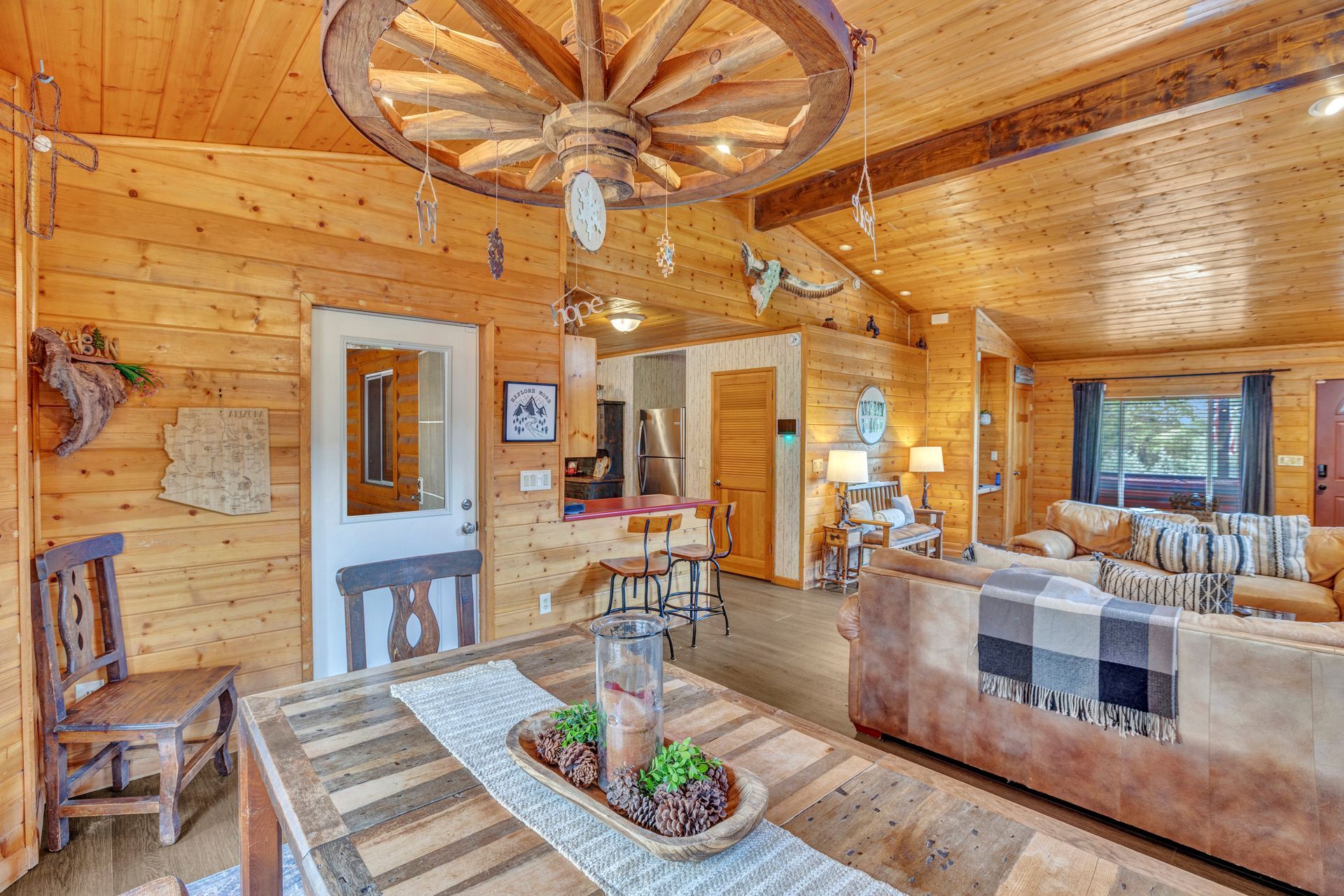 Rustic log cabin living room with wooden walls, wagon-wheel chandelier, and cozy seating area