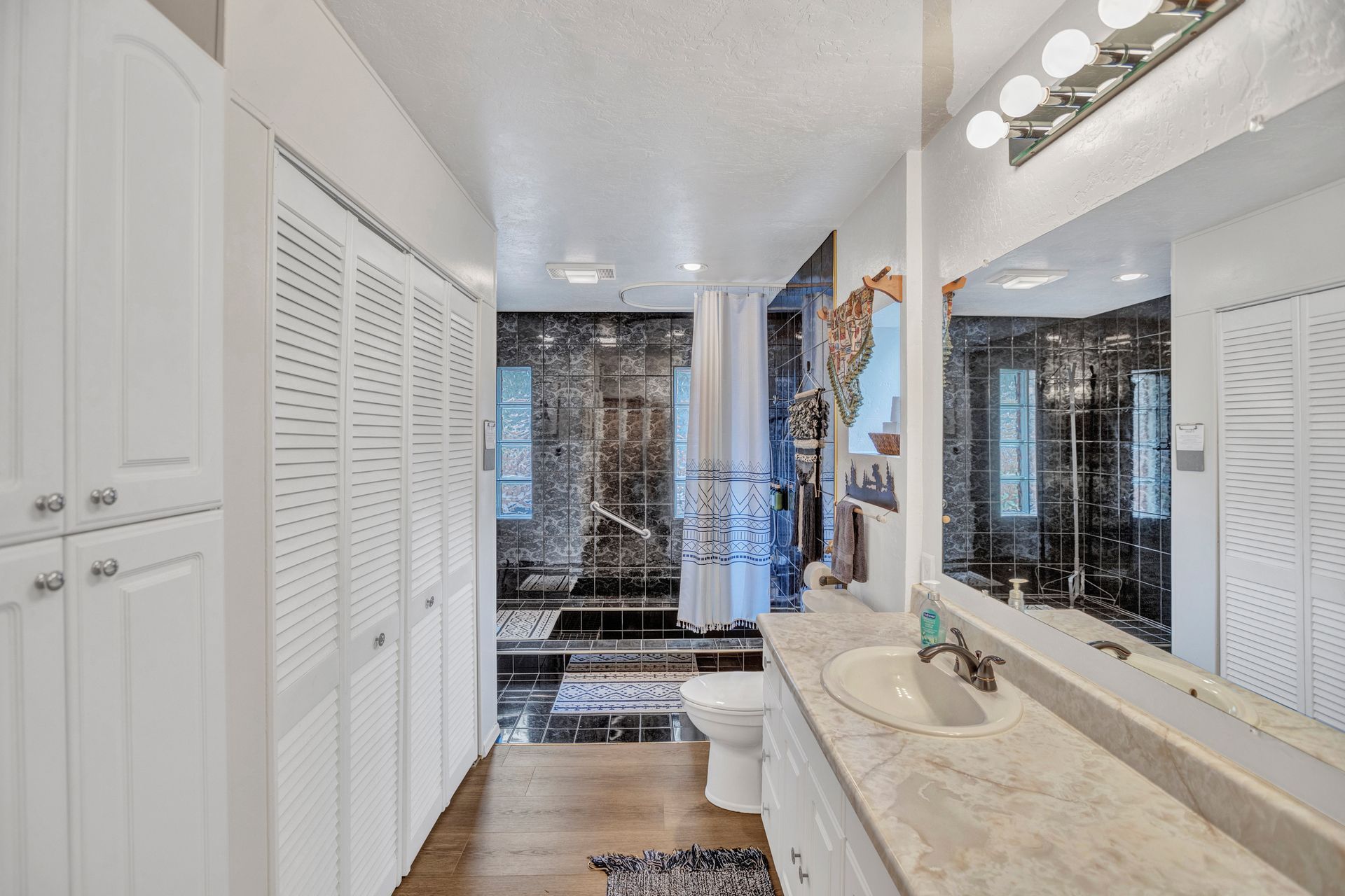 Bright white bathroom with double vanity, large mirror, and tiled shower area.
