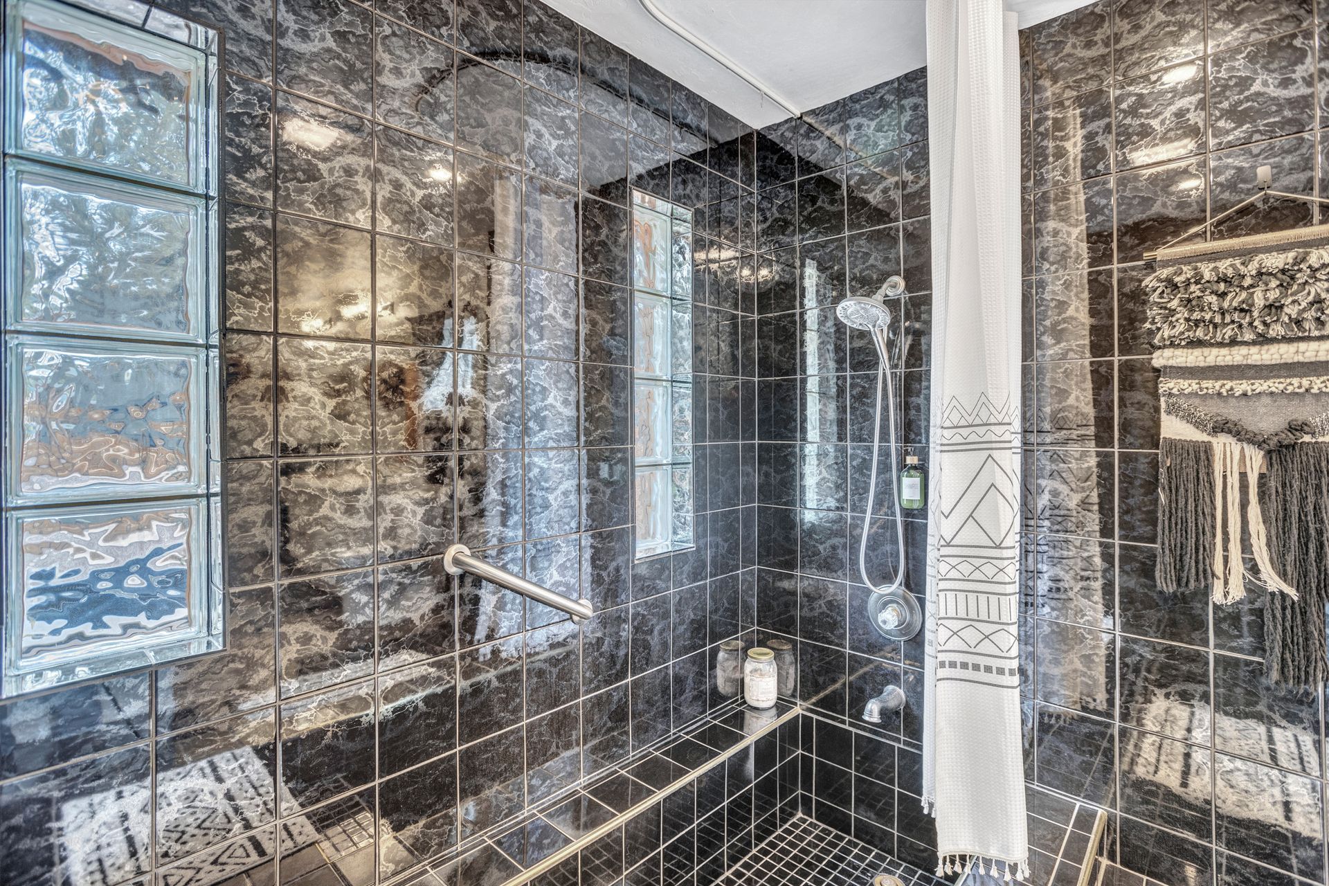 Modern black-and-white bathroom with tiled shower, glass door, and wall-mounted towel rack
