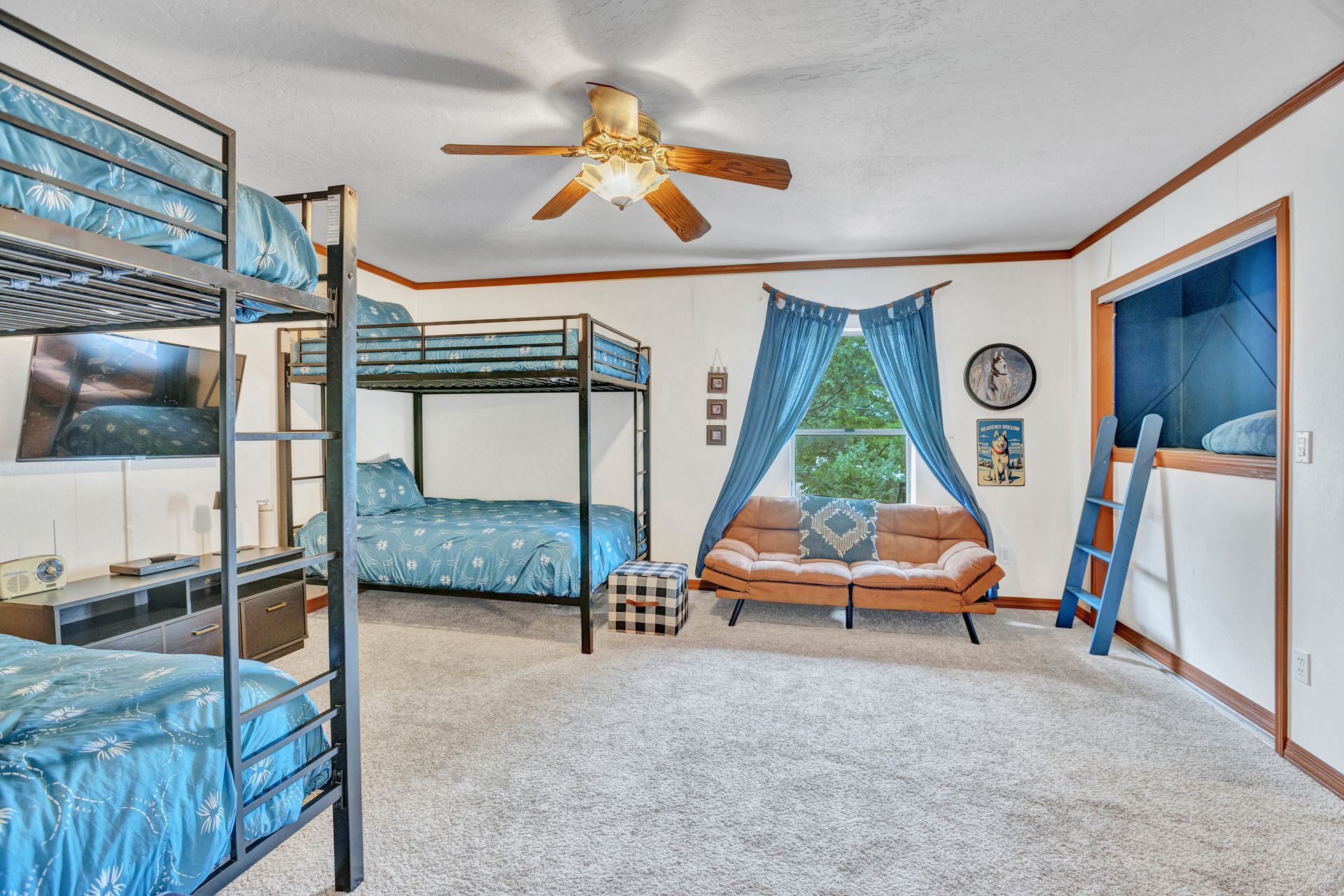 Bedroom with blue bunk beds, a blue canopy bed, and a wooden swing chair under a ceiling fan