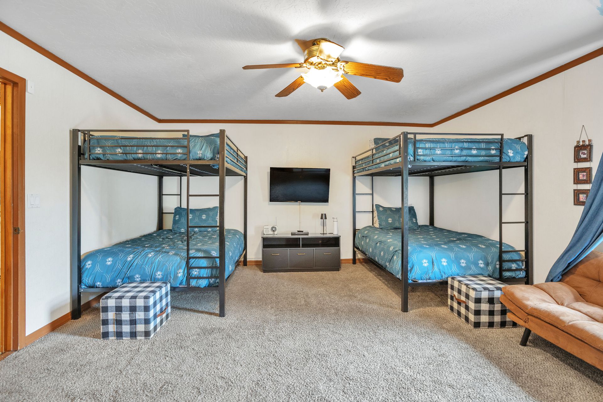 Dorm-style bedroom with two bunk beds, a TV, ceiling fan, and carpeted floor