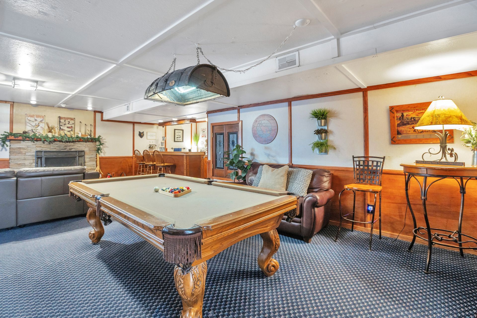 Recreation room with pool table, leather chairs, bar stools, and warm orange decor