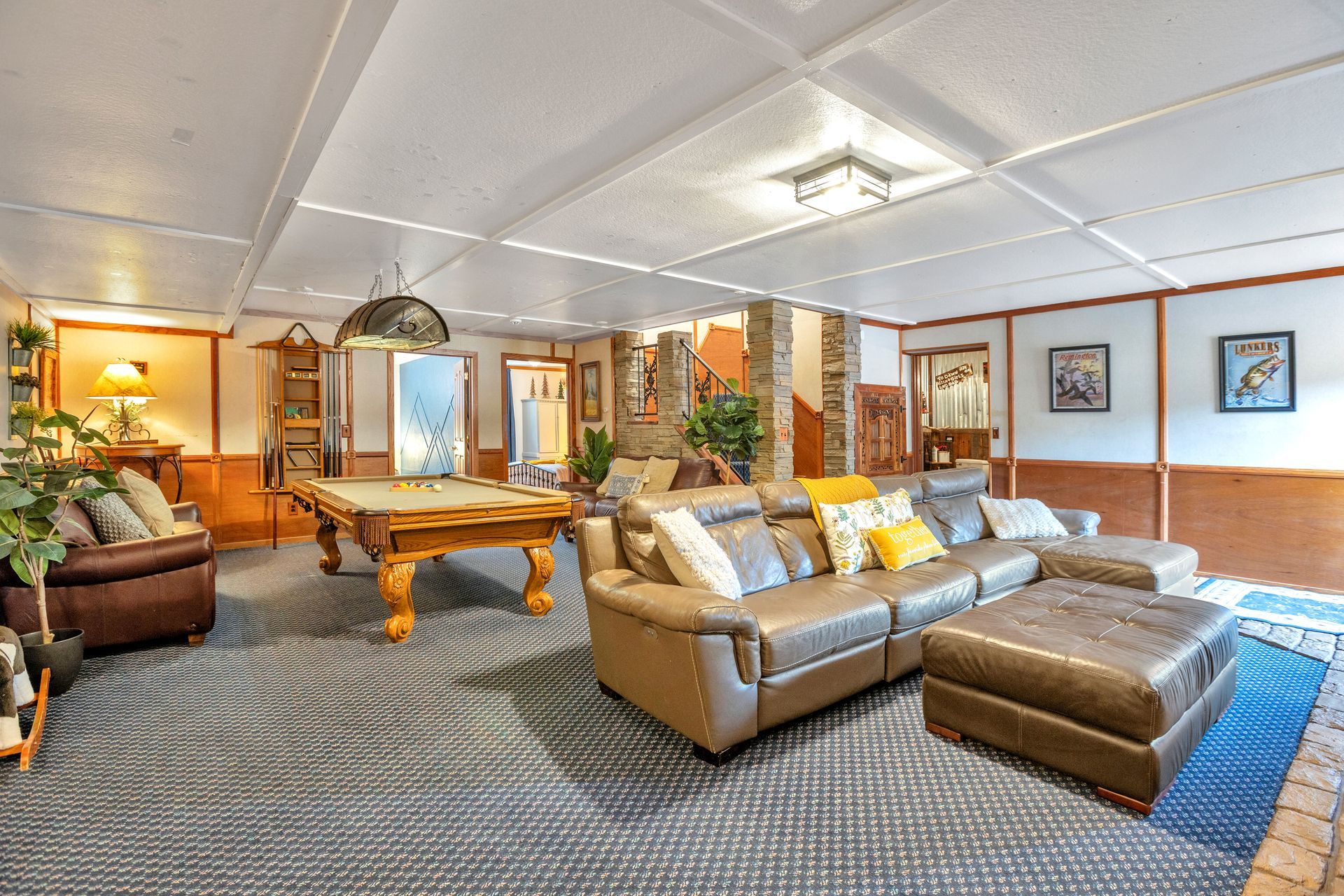 Spacious living room with gray sofa, ottoman, pool table, and warm ceiling lights