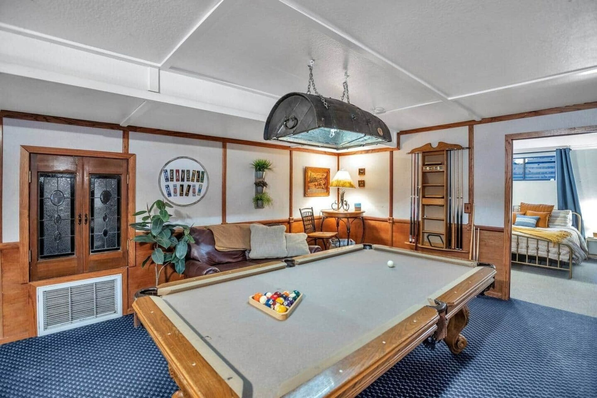 Spacious game room with a pool table, blue carpet, couch, wall decor, and large windows