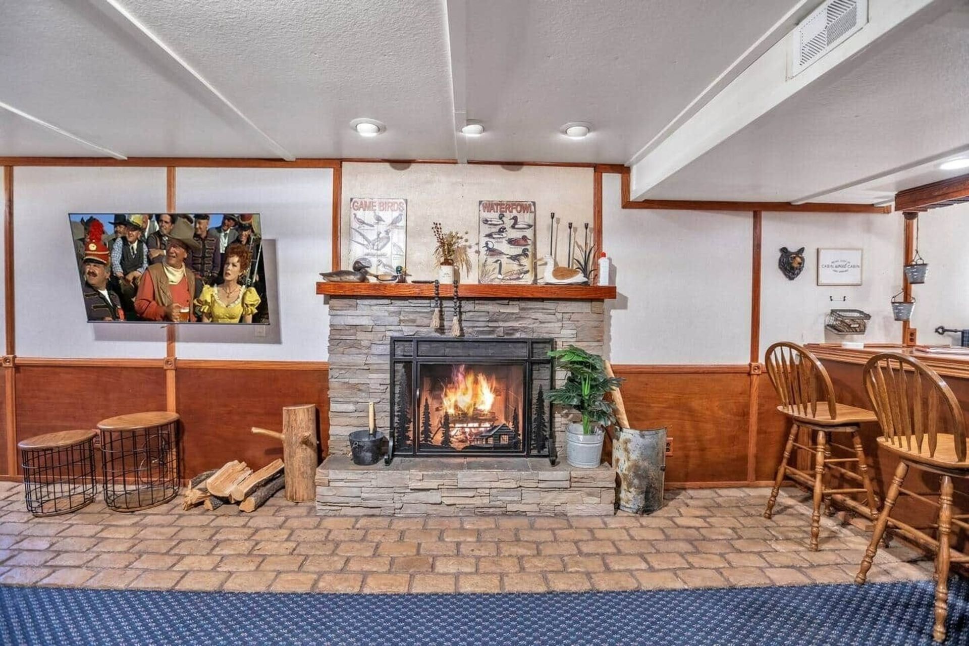 Cozy restaurant lounge with a lit stone fireplace, wood paneling, tiled floor, and wicker chairs and tables