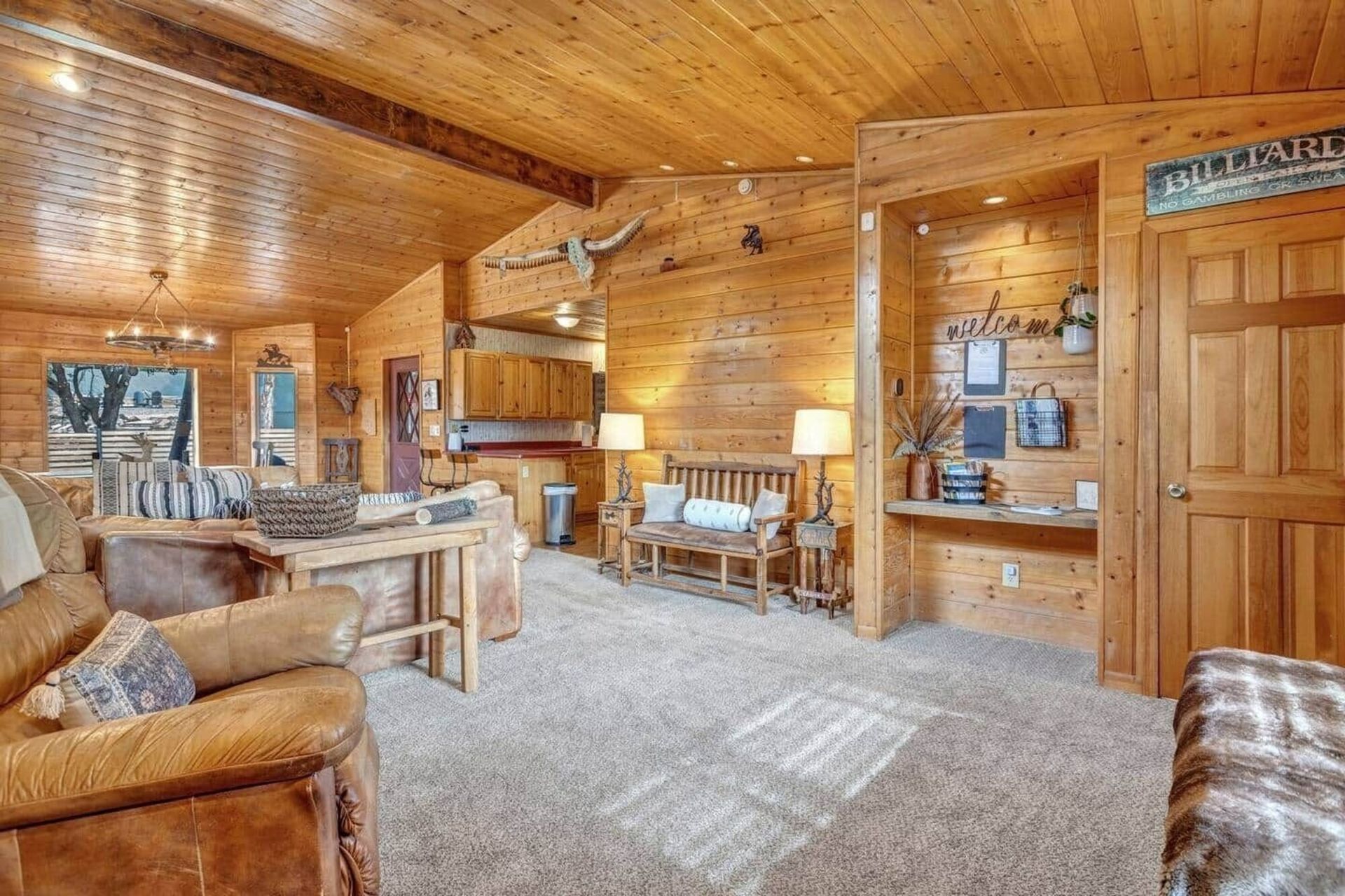 Cozy wood-paneled cabin living room with leather chairs, fireplace, and carpeted seating area