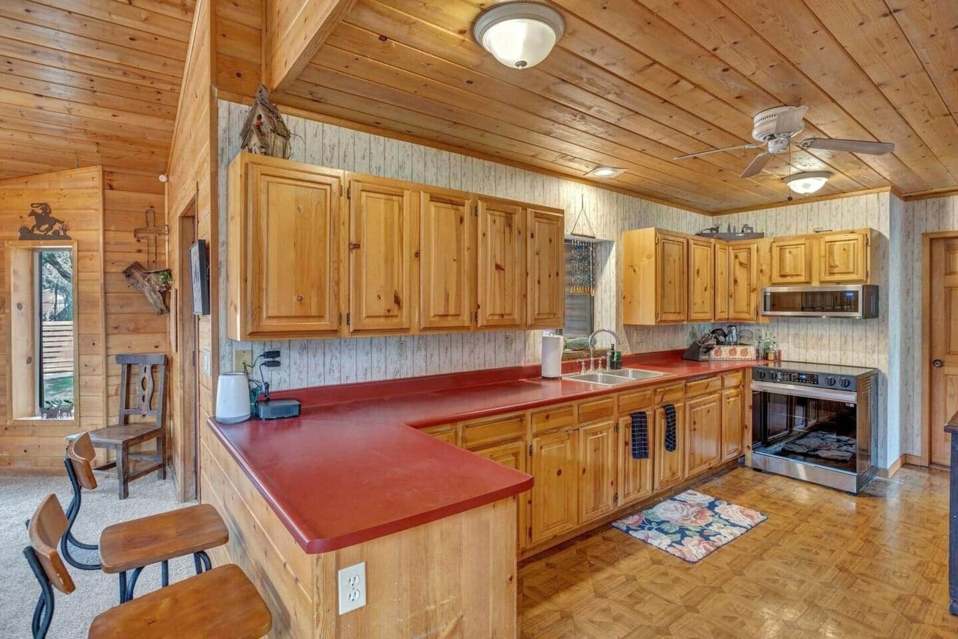 Wooden kitchen with red countertops, oak cabinets, stove, and ceiling lights