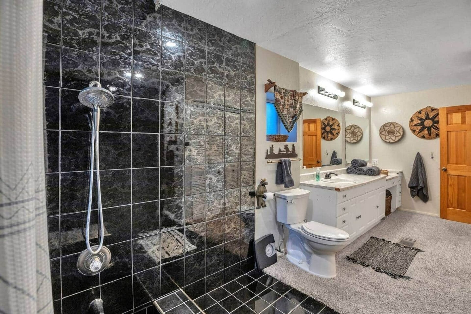 Modern bathroom with black tile shower, white vanity, toilet, and rustic decor
